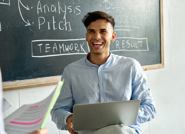 Young happy indian latin man student with laptop laughing at office meeting